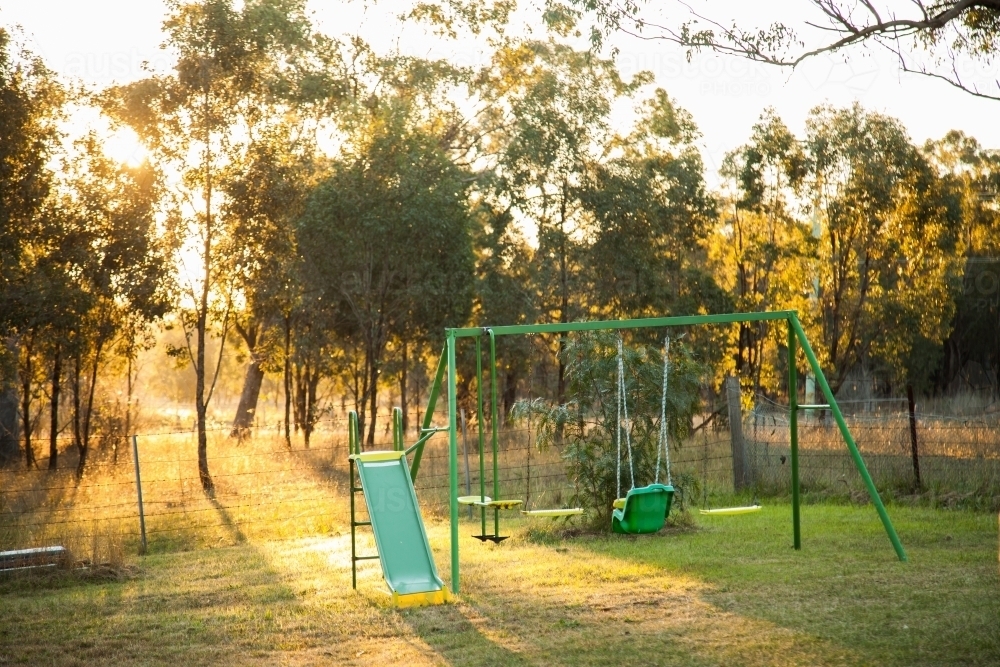 Children's swing set in golden afternoon light - Australian Stock Image