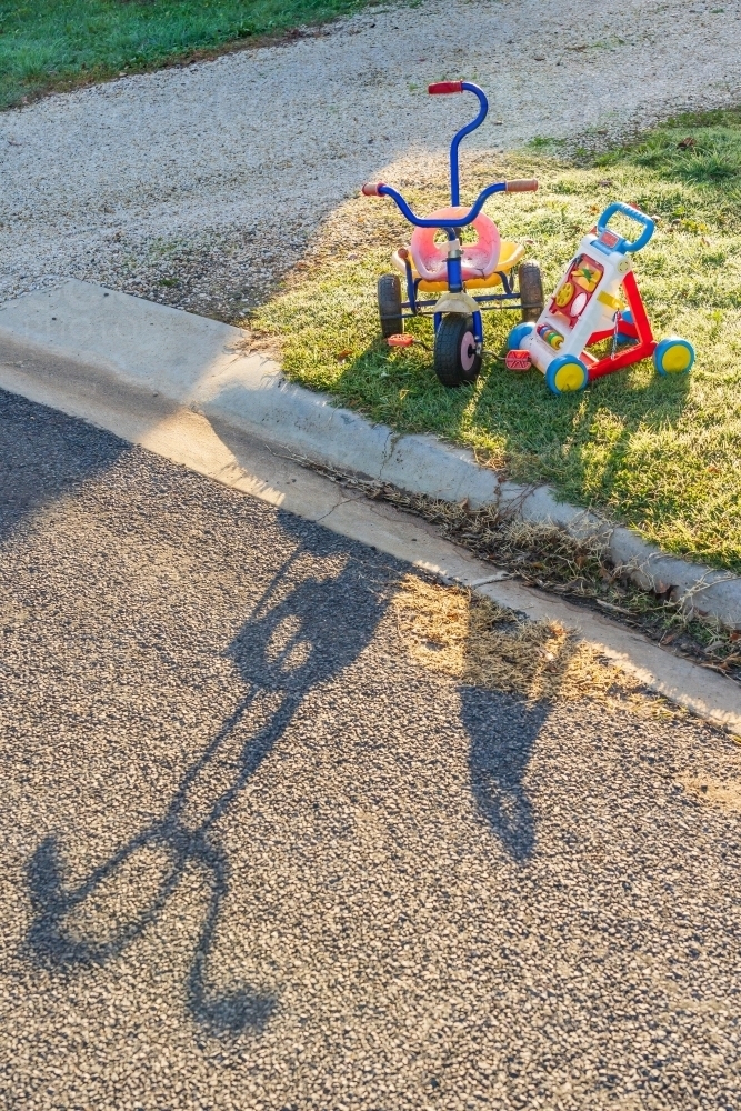 Children's toys sitting on the roadside on early morning sunshine - Australian Stock Image