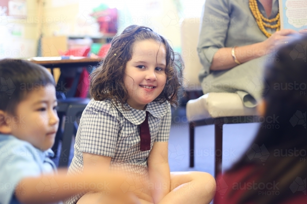 Children sitting on the floor at the feet of their teacher - Australian Stock Image