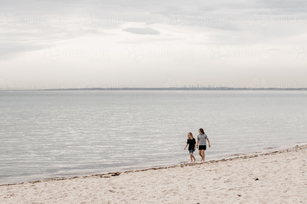 children walking along the beach with Melbourne City in the background - Australian Stock Image