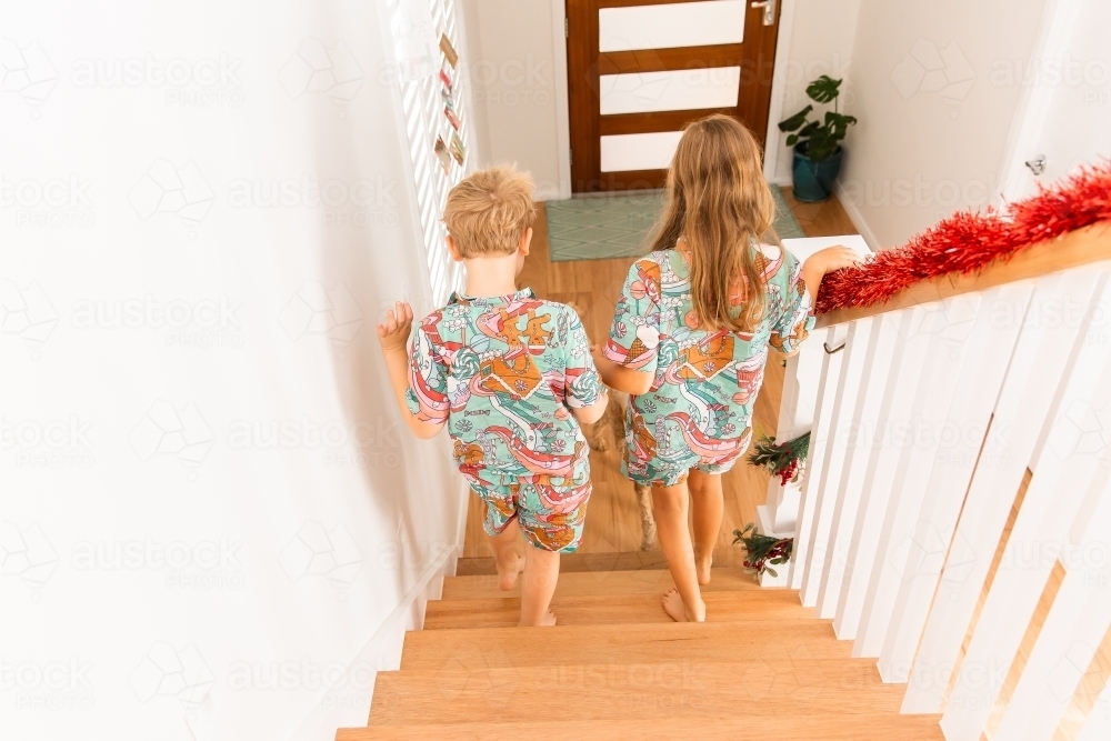 children walking downstairs together in matching Christmas pyjamas - Australian Stock Image