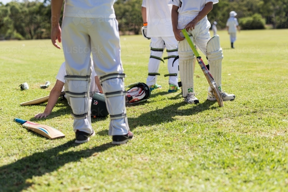 Children wearing pads waiting to bat during a game of cricket - Australian Stock Image