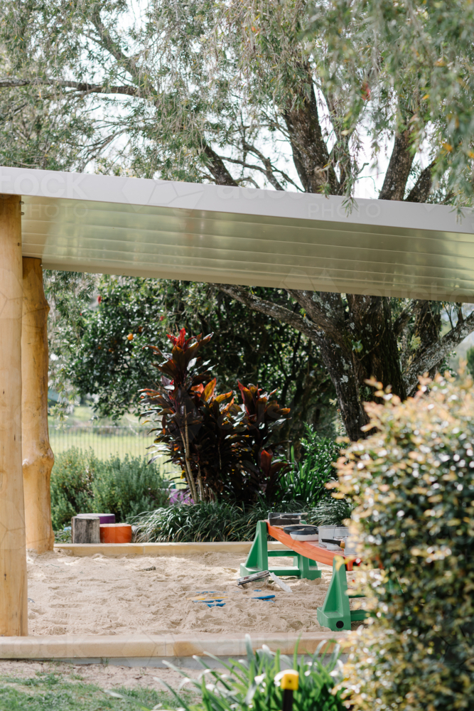 Childrens wooden sandpit with roofing in the garden. - Australian Stock Image