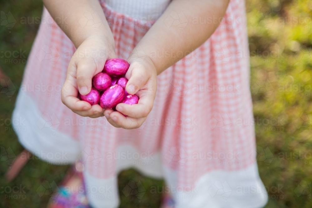 Childs hands hold out pink easter eggs - Australian Stock Image