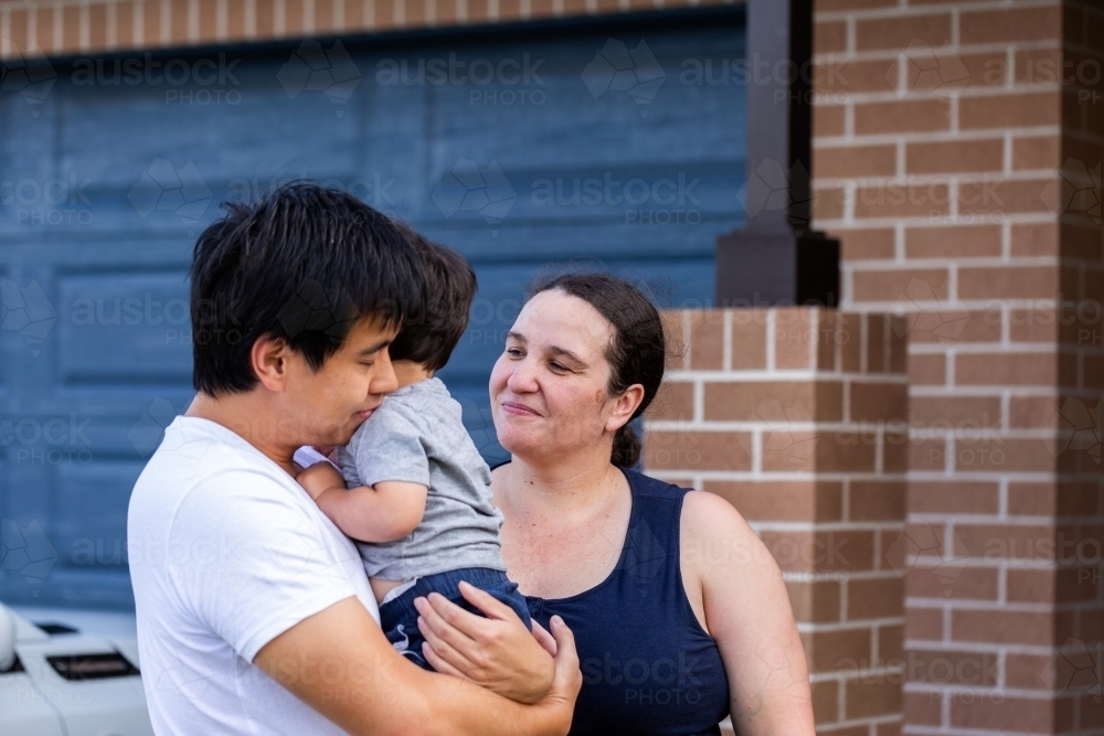 Chinese Australian dad hugging his son outside home comforting him - Australian Stock Image
