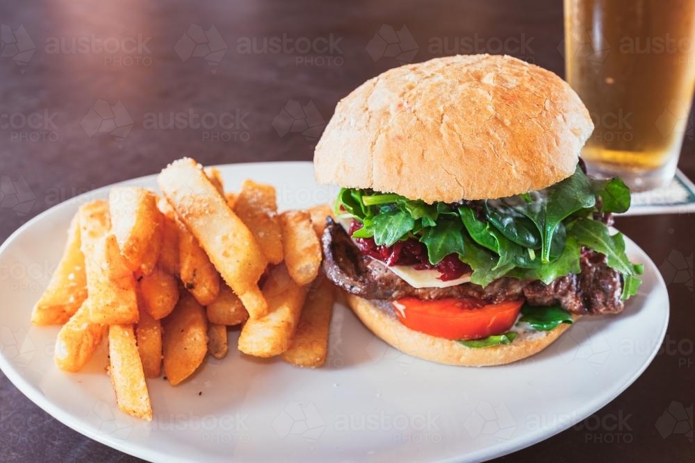 Chips, burger with steak and beetroot and a beer for lunch - Australian Stock Image