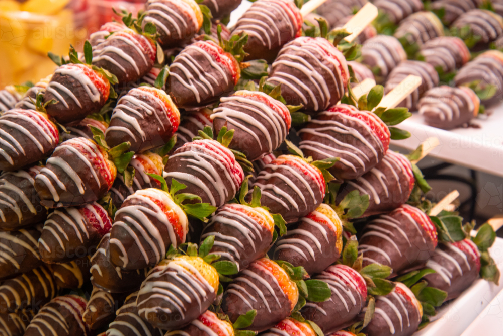 Chocolate coated strawberries stacked up for sale at the market - Australian Stock Image