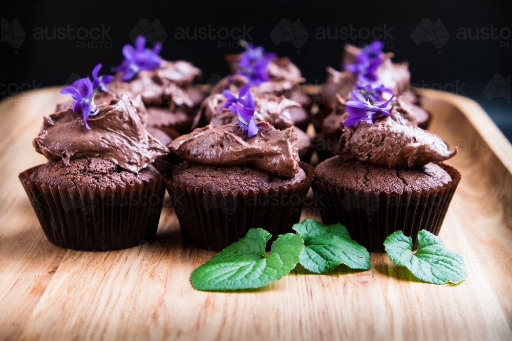 Chocolate cup cakes with frosting and flowers - Australian Stock Image