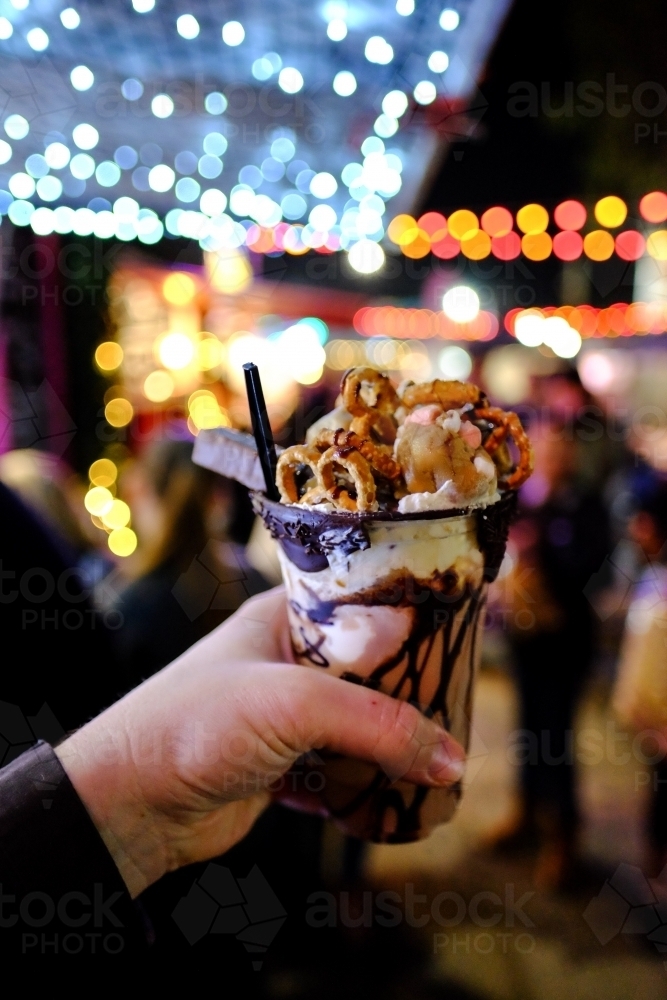 Chocolate milkshake with cream, chocolate sauce and pretzels at a night market - Australian Stock Image