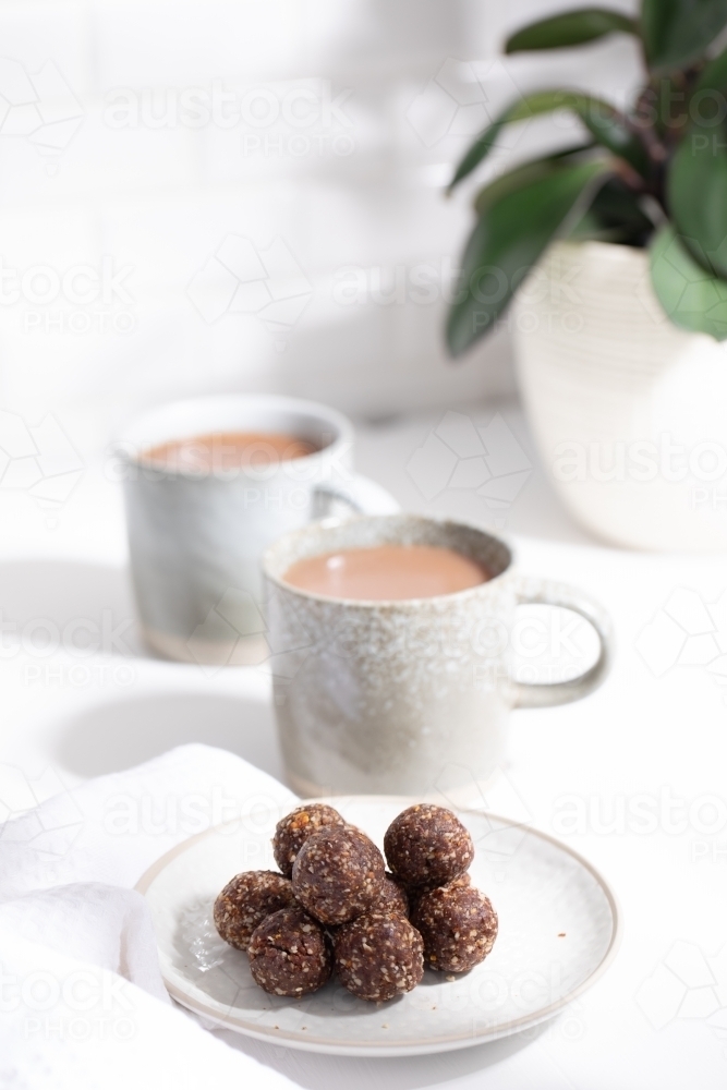Chocolate protein balls on a white kitchen bench with two mugs - Australian Stock Image