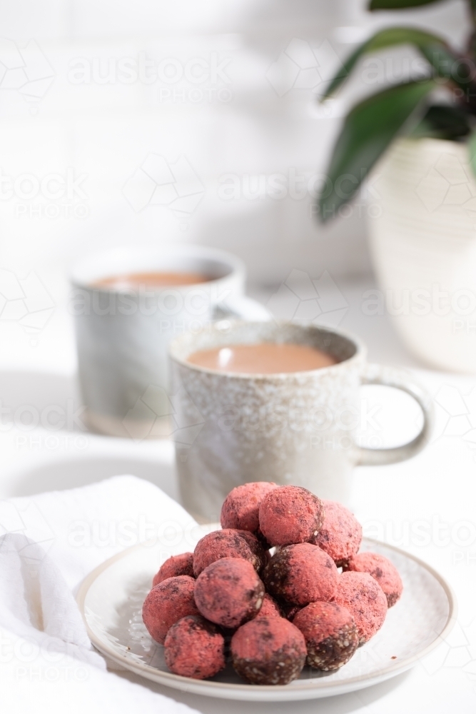 Chocolate protein balls on a white kitchen bench with two mugs - Australian Stock Image