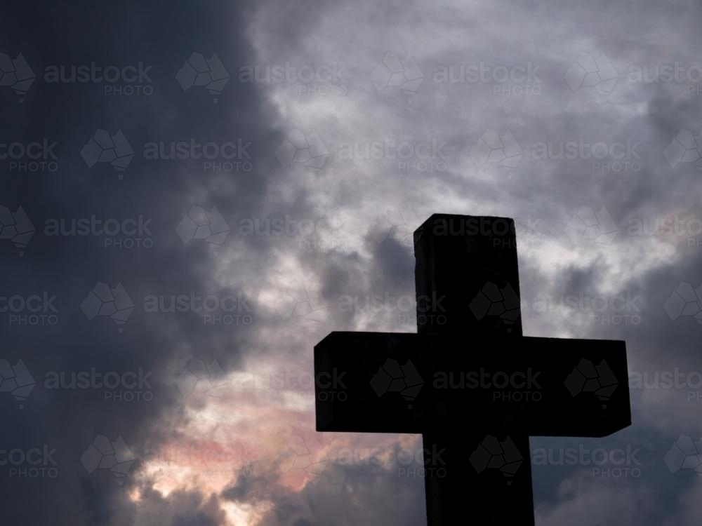 Christian cross silhouetted against a stormy sunset sky - Australian Stock Image