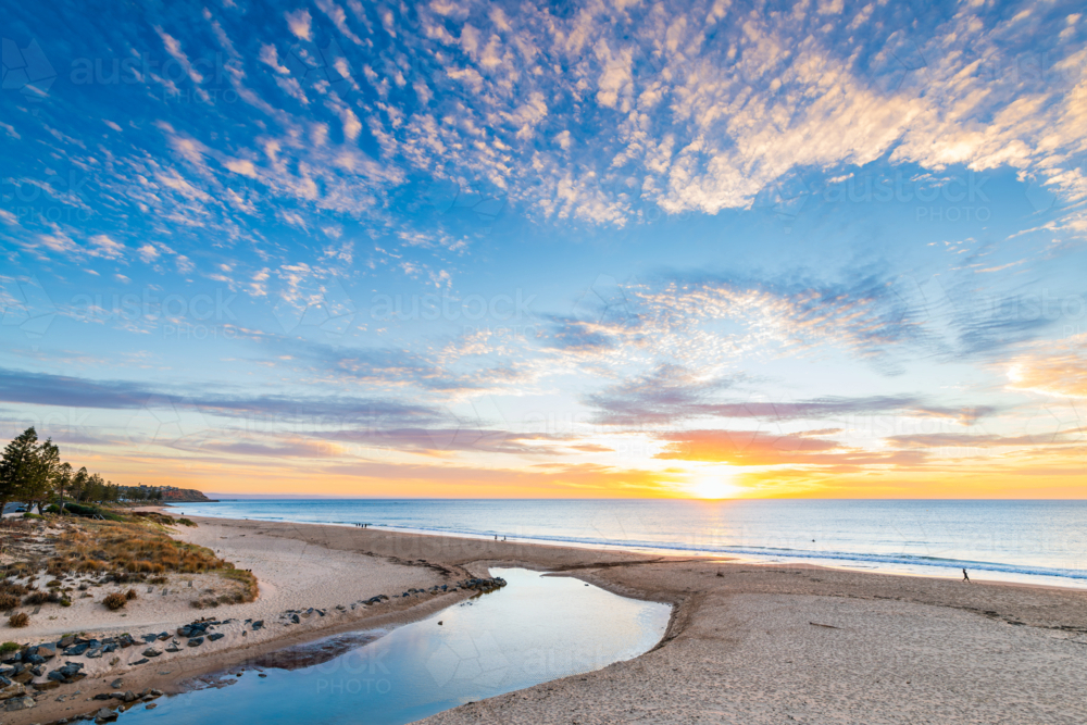 Christies Beach with people walking along the ocean shore at sunset, South Australia - Australian Stock Image