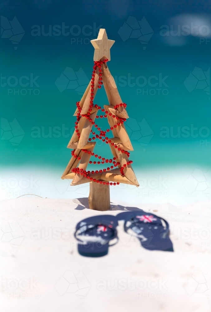 Christmas at the beach, sun, surf and leisure. A pair of thongs and small driftwood Christmas tree - Australian Stock Image