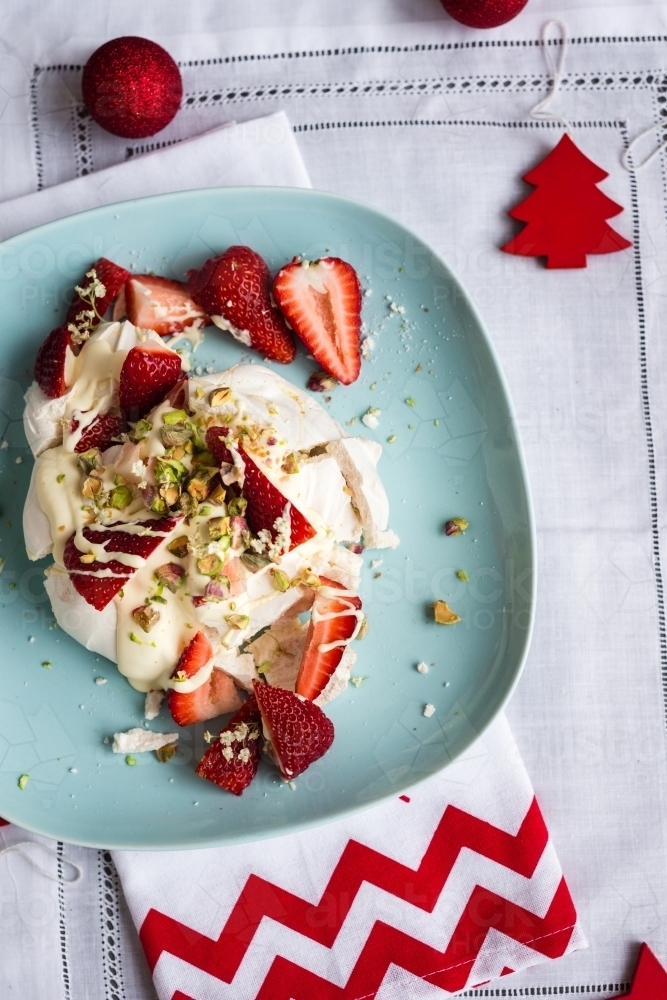 christmas dessert, single pavlova xmas dessert on a blue plate, with messy strawberry cream topping - Australian Stock Image