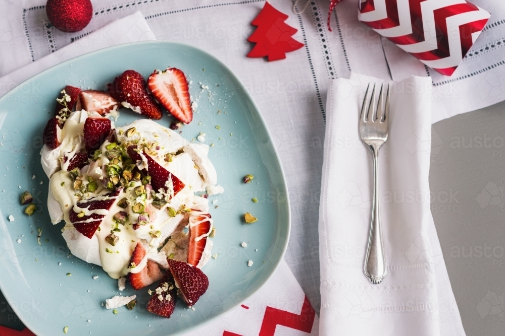 christmas dessert, single pavlova xmas dessert on a blue plate, with messy strawberry cream topping - Australian Stock Image