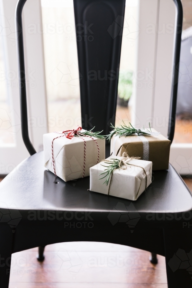 Christmas gifts beautifully wrapped on a contemporary dining chair - Australian Stock Image