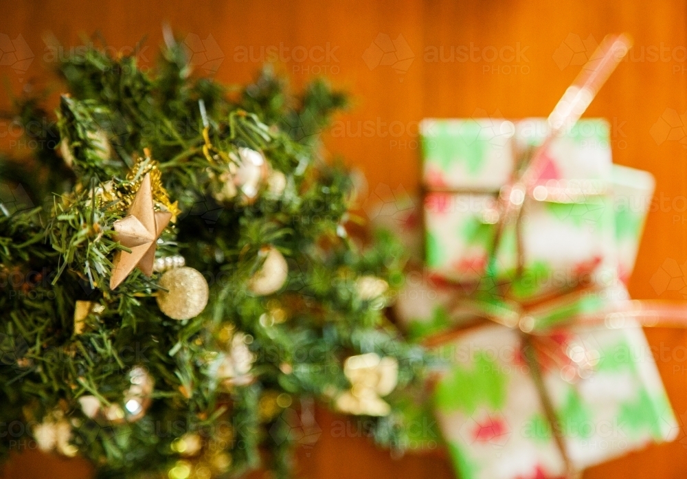 Christmas gifts under a small decorated tree with a star on top - Australian Stock Image