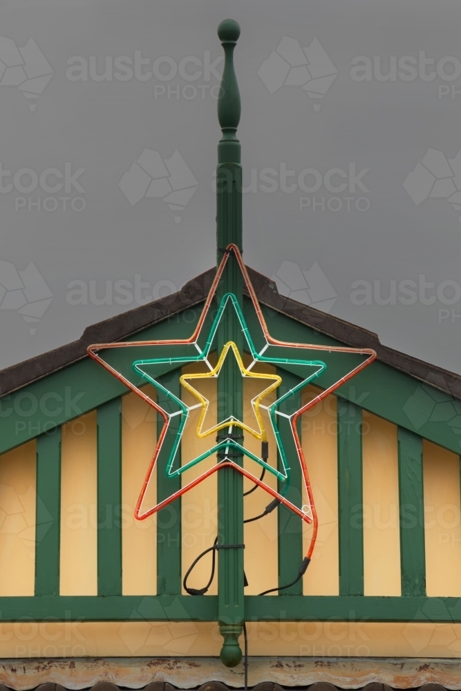 Christmas star decoration neon light on house gable roof - Australian Stock Image