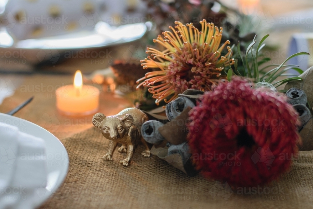 Christmas table setting with native flowers, candle and gold koala ornament - Australian Stock Image