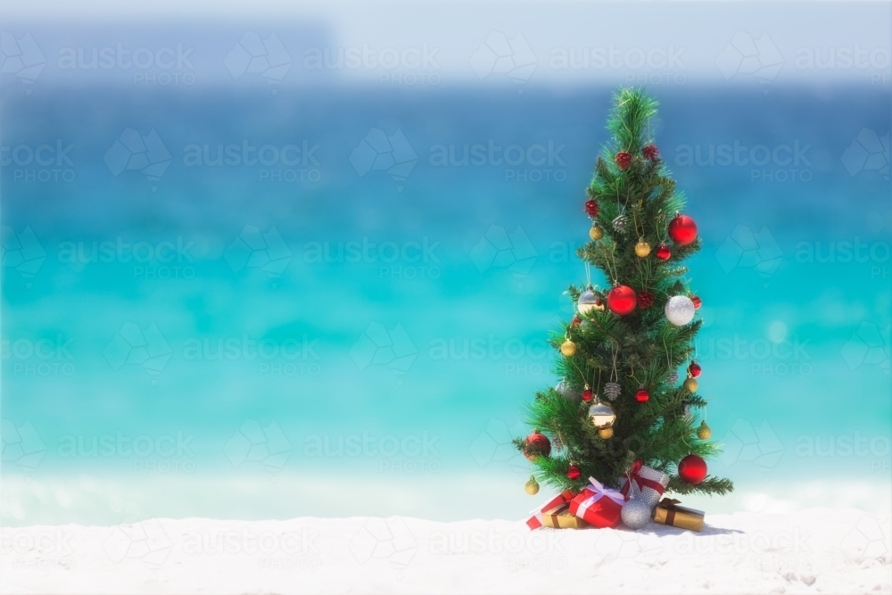 Christmas tree decorated with colourful baubles and presents underneath it - Australian Stock Image