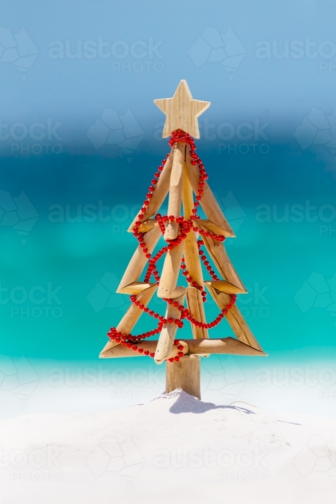 Christmas tree on idyllic white sandy beach with ocean background blur - Australian Stock Image
