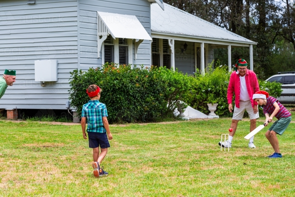 Christmastime backyard cricket game in yard of country style weatherboard home - Australian Stock Image