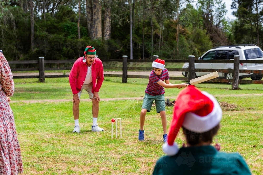 Christmastime backyard cricket game with ball about to get kid out - Australian Stock Image