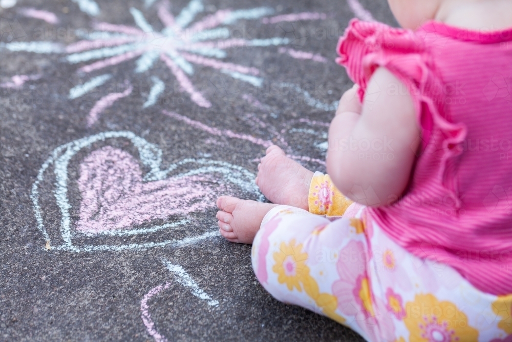 Chubby seven month old baby feet with chalk drawings on concrete - childhood - Australian Stock Image
