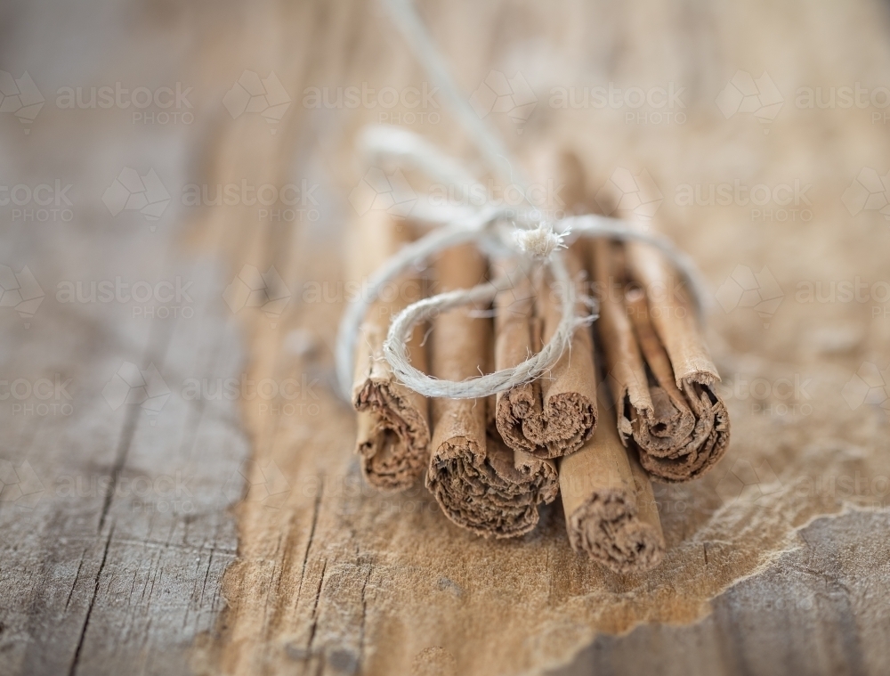 cinnamon stick tied in a bunch with string on wooden board - Australian Stock Image