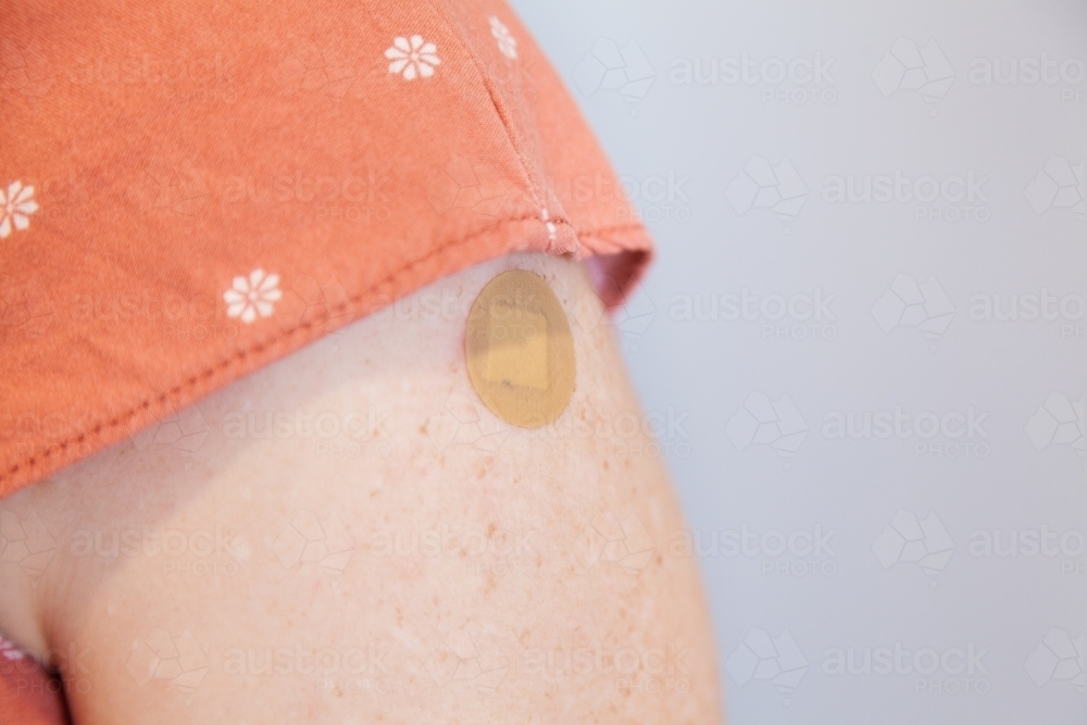 circular band-aid on person's arm after getting dose of covid vaccination - Australian Stock Image