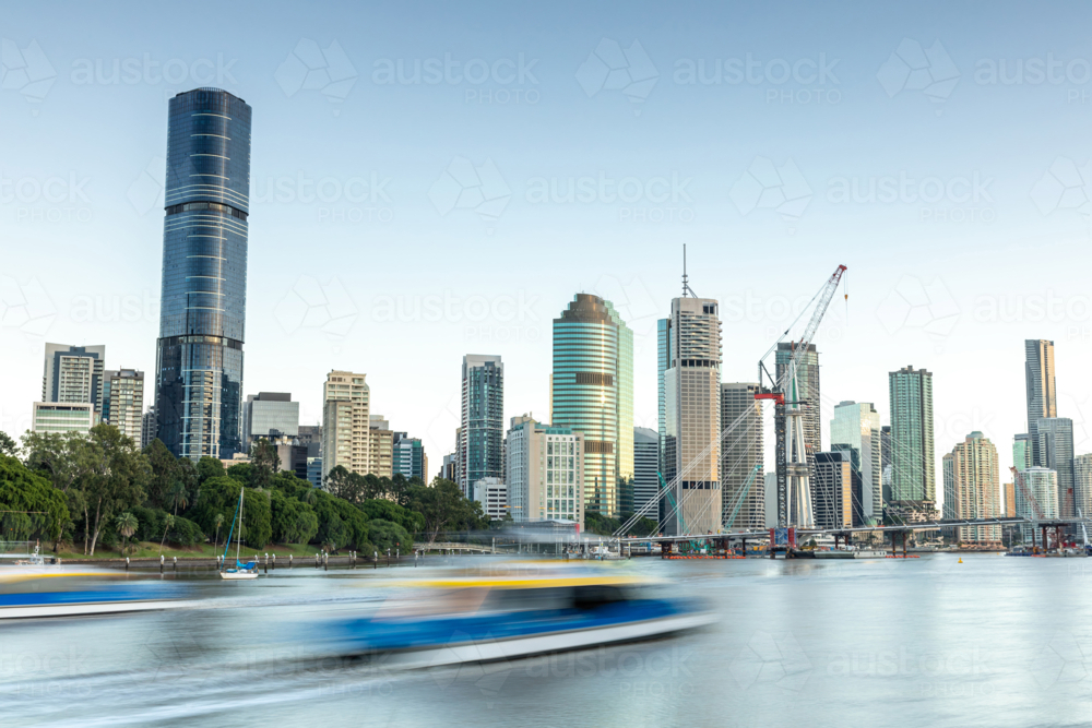 City-Cat boat speeding on river with city skyline - Australian Stock Image