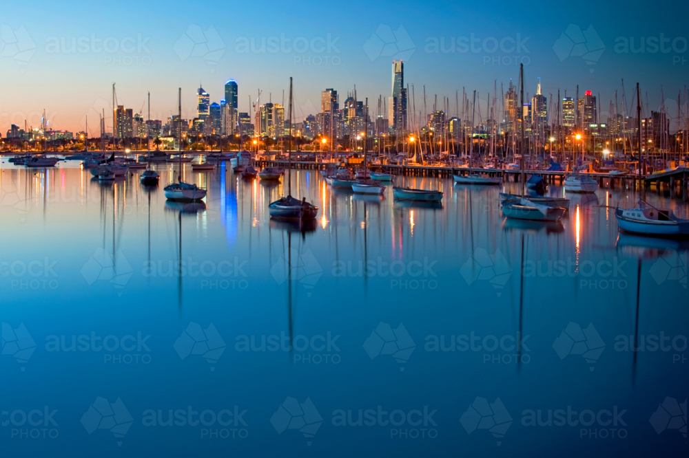City skyline glowing over a calm marina at dusk - Australian Stock Image