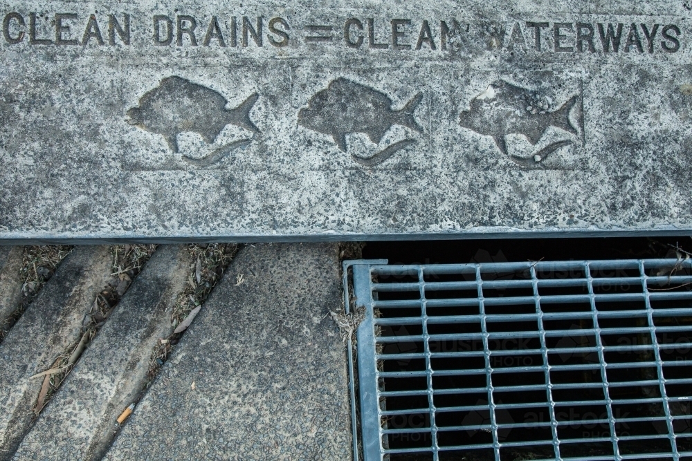 Clean drains = clean waterways written on gutter beside road - Australian Stock Image
