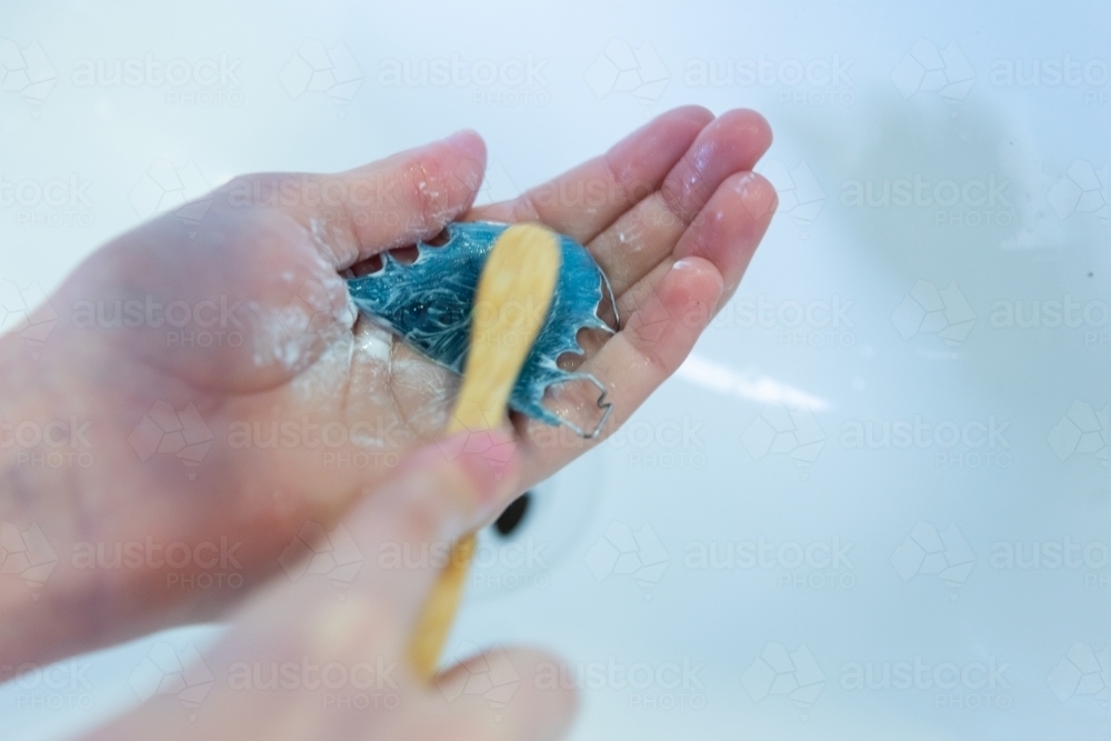 Cleaning orthodontic retainer at sink - Australian Stock Image