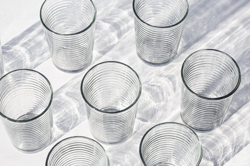 Clear cups with light shining through them creating abstract texture - Australian Stock Image