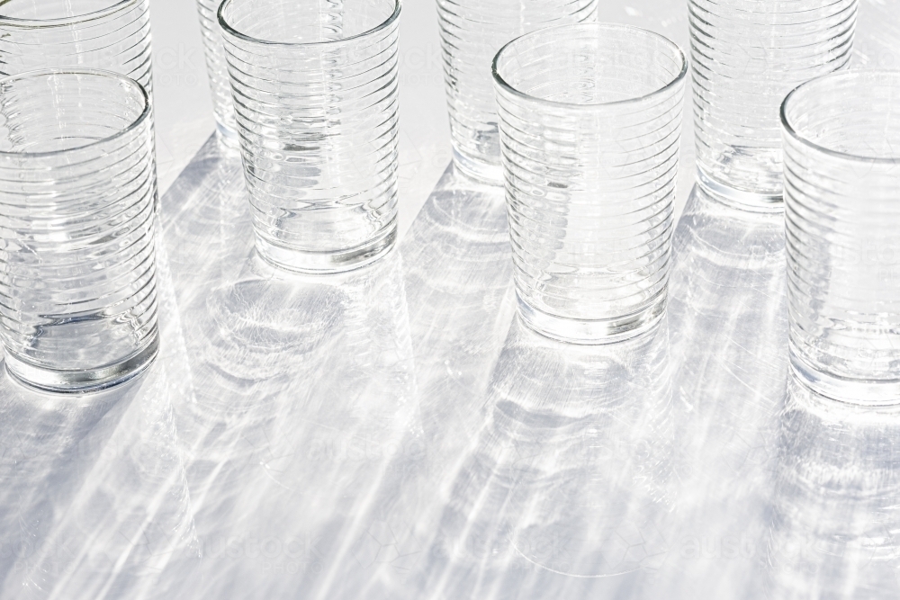 clear glasses reflecting light with reflected rippled shadow pattern - Australian Stock Image