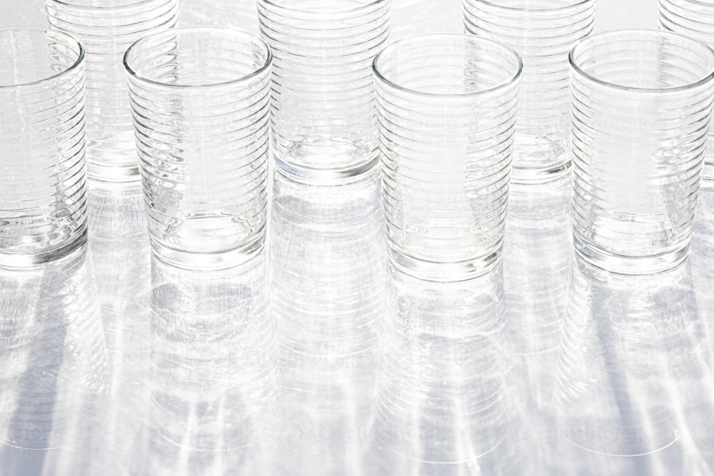 clear glasses reflecting light with reflected rippled shadow pattern - Australian Stock Image
