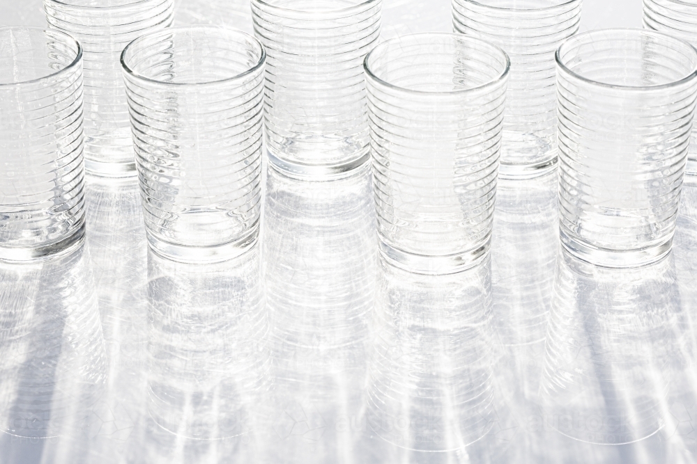 clear glasses reflecting light with reflected rippled shadow pattern - Australian Stock Image