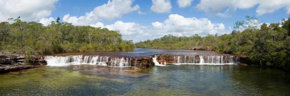 Clear water flows over terraced rock at a natural bush waterfall. - Australian Stock Image