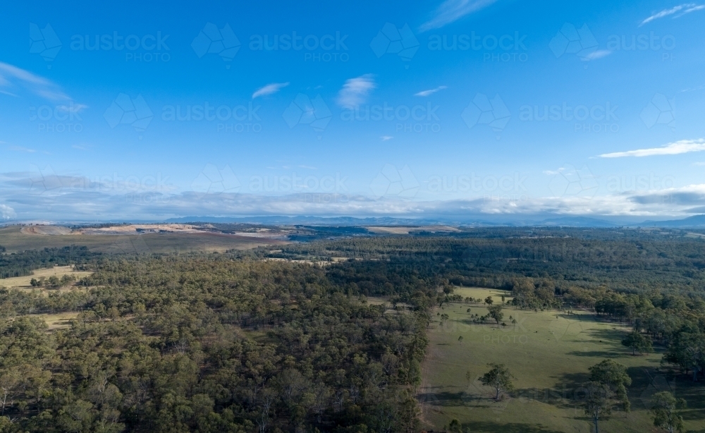 cleared paddock and uncleared land with open cut coal mine in the distance - Australian Stock Image