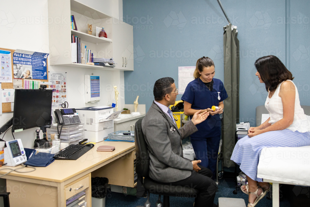 Clinical nurse handing out specimen container to senior patient - Australian Stock Image