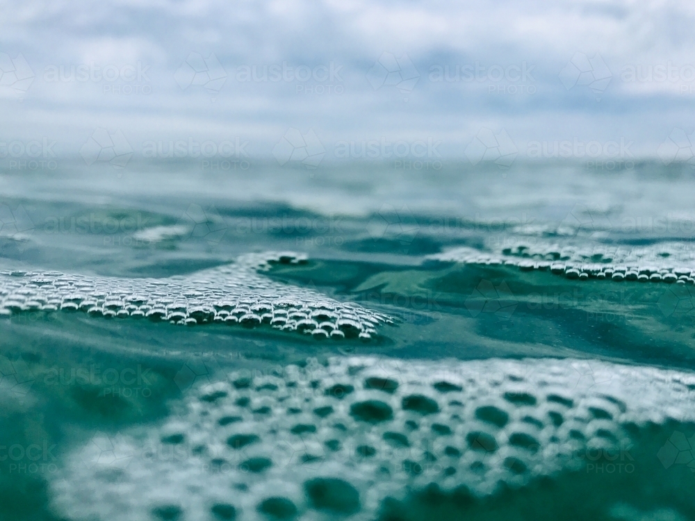 Close up Bubbles on Surface of ocean with overcast sky in background - Australian Stock Image