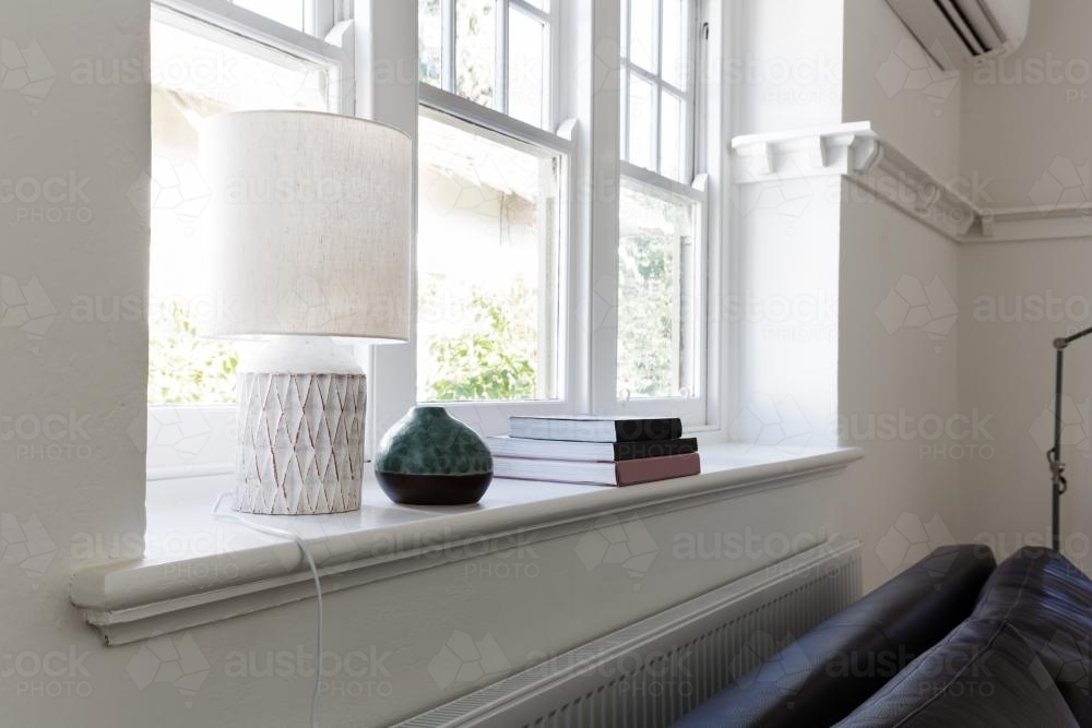 Close up details of lamp books and ornament objects on windowsill - Australian Stock Image