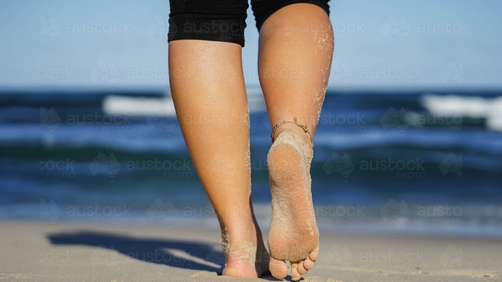 Close up low angle of feet walking away on the beach - Australian Stock Image