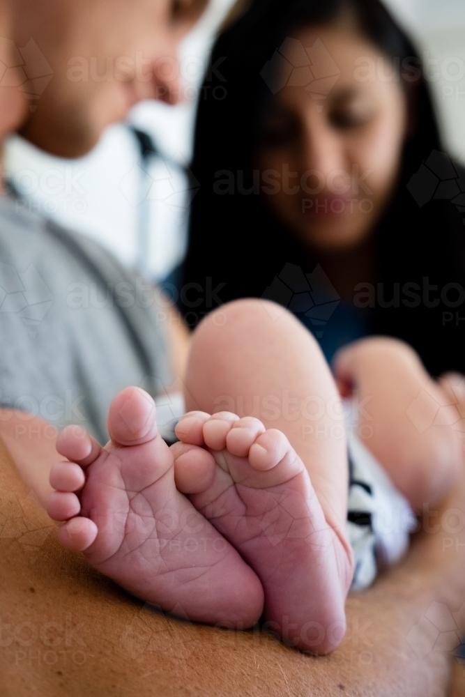 Close up Newborn feet with parents in background - Australian Stock Image