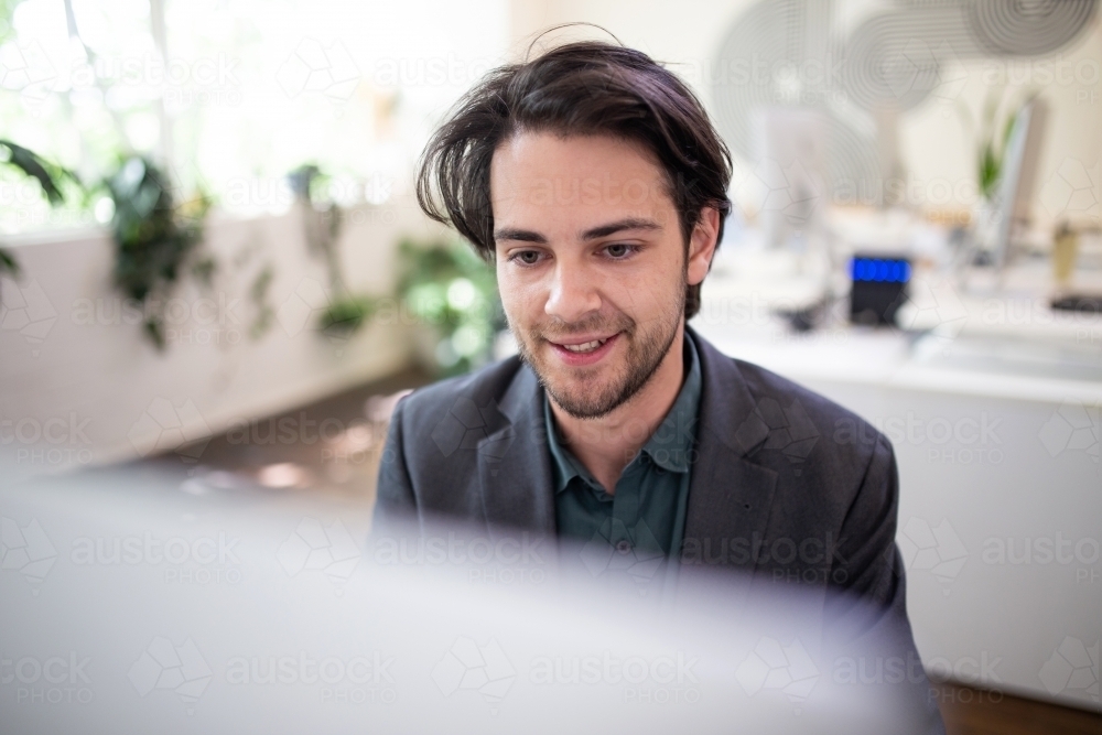 Close-up of 20-something male looking at computer screen - Australian Stock Image