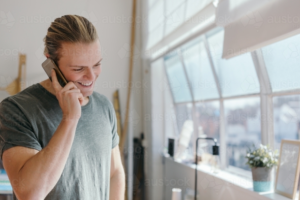 Close up of a blonde guy on the phone indoors - Australian Stock Image