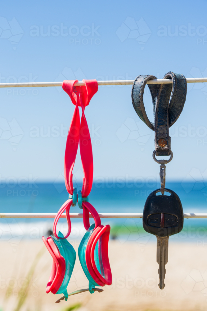 Close up of a car key and swimming goggles hanging on a fence at the beach - Australian Stock Image