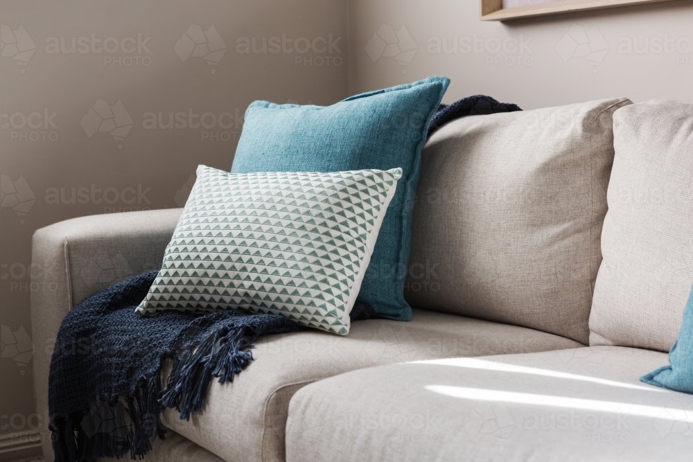 Close up of a fabric sofa with styled cushions and throw - Australian Stock Image